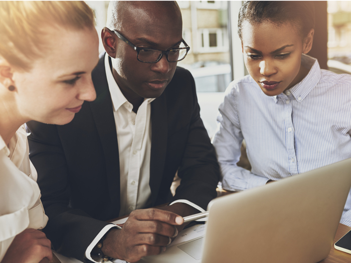 Three office workers look at laptop