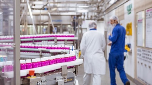 Worker in a blue boiler suit and worker in white lab coat talking in a Gaviscon factory