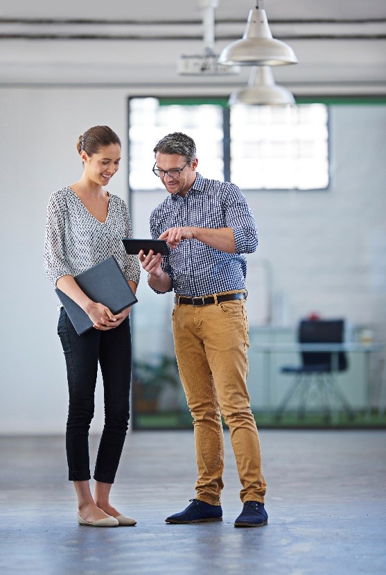 Two people stand together in room looking at a tablet device