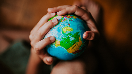 Children's hands holding toy globe