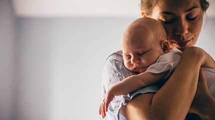 Parent standing up cradling young baby