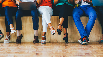 Group of people sitting on a stage with just their legs visible 