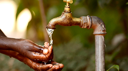 Person using outdoor tap to wash hands