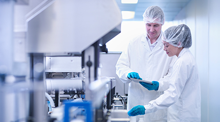 Two laboratory workers looking at a tablet device while in a lab