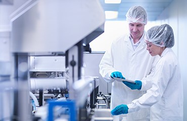 Two laboratory workers looking at a tablet device while in a lab