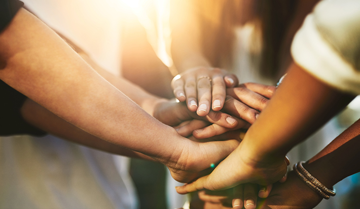 Diverse group of people put their hands together