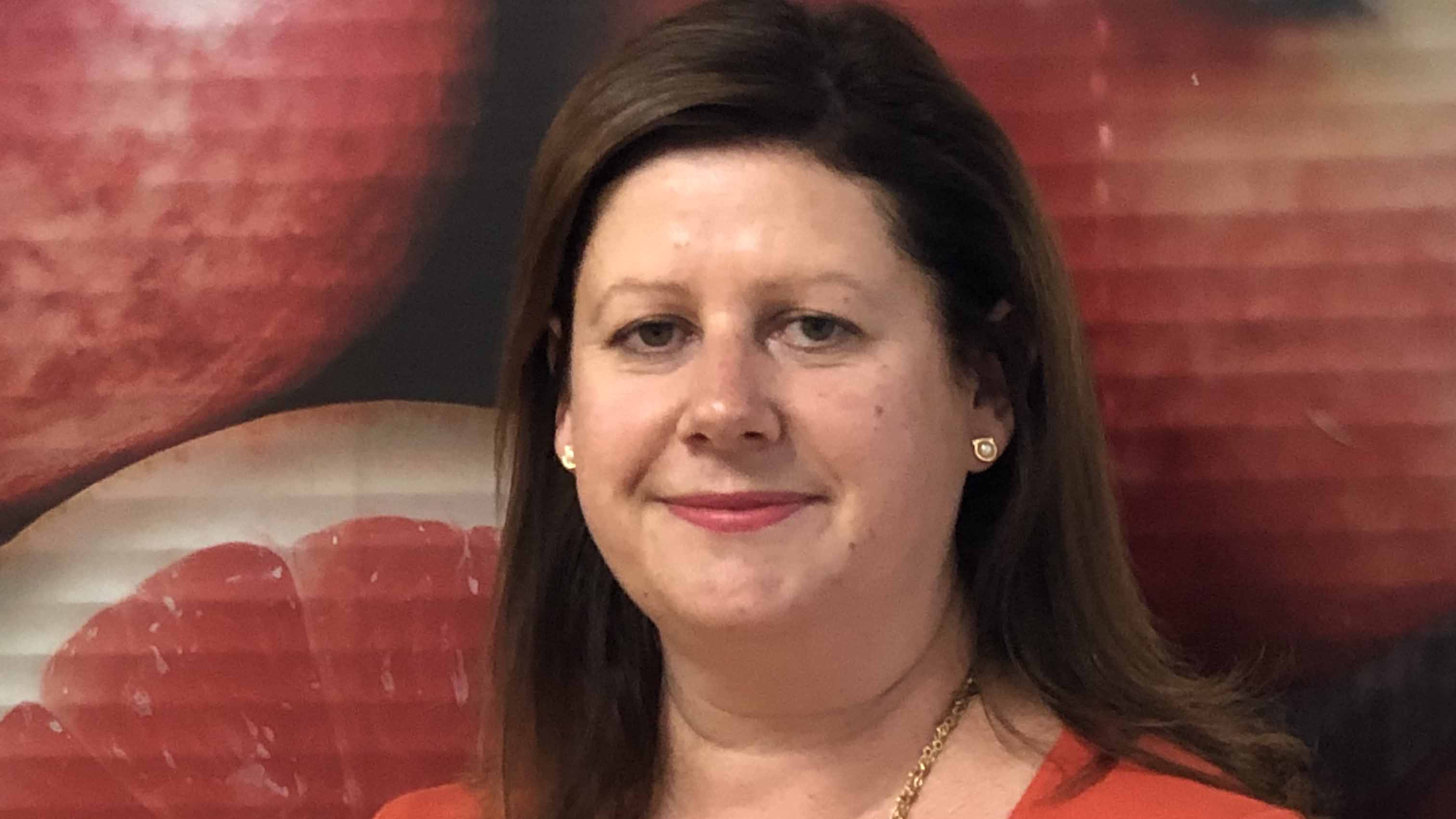 Clare headshot in front of wall with grapefruit wallpaper