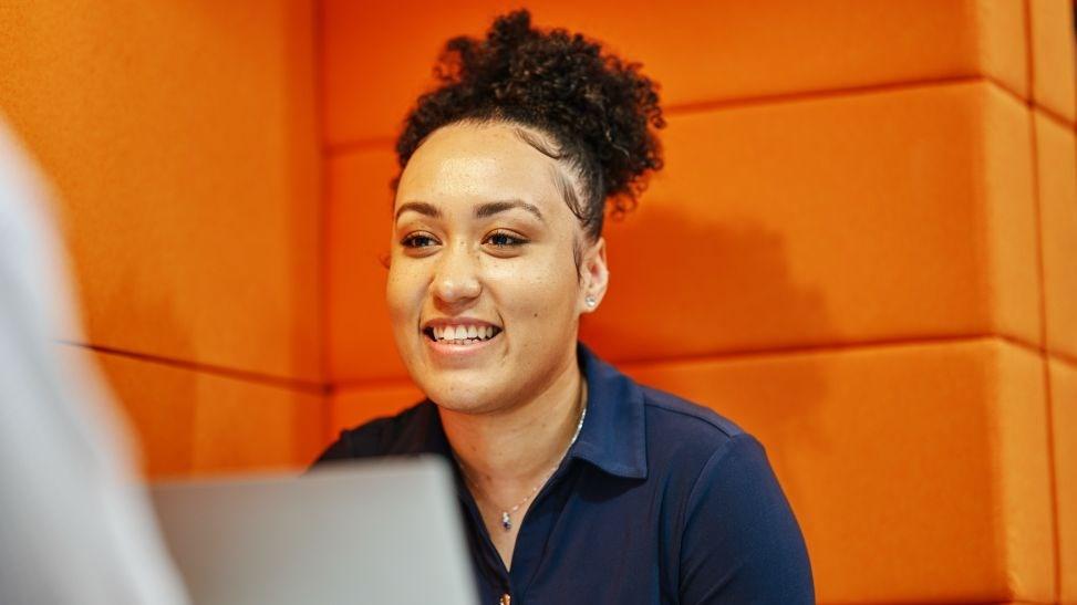 Young woman smiling against an orange background