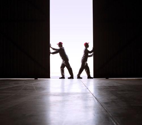 Two workers opening large sliding doors