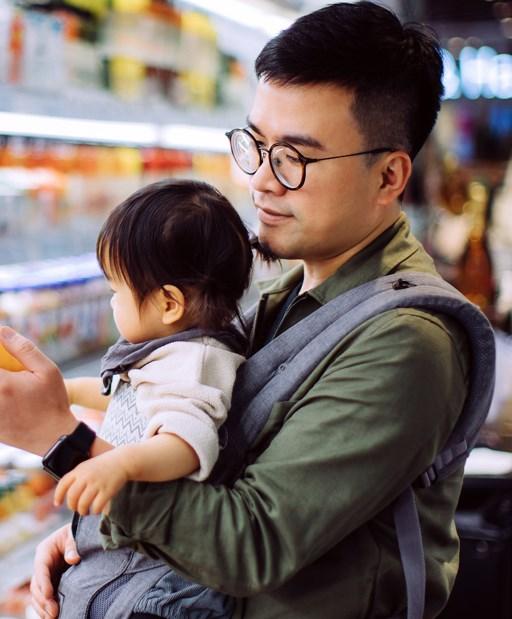 Young Asian father with cute little daughter grocery shopping for fresh fruit juice in supermarket.
