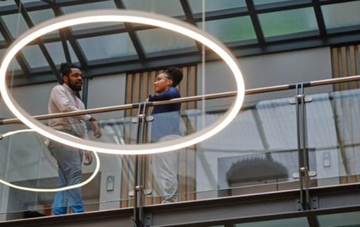 Colleagues talking while framed in a ring ceiling light