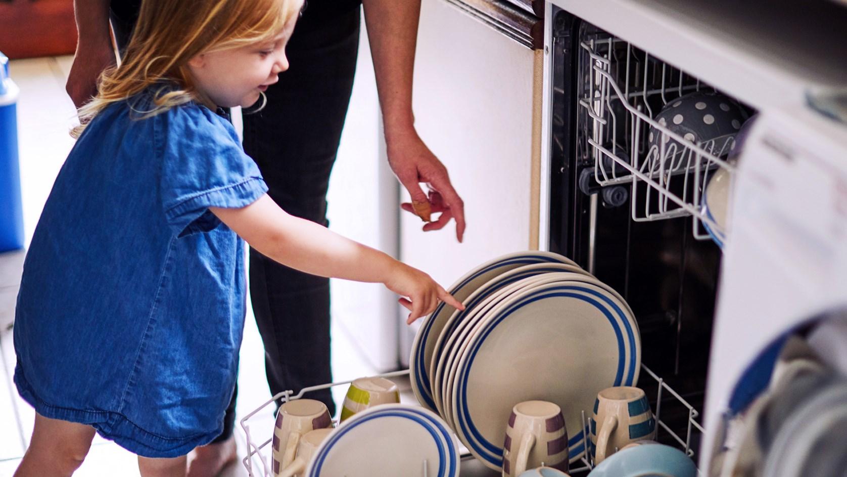 Child helping adult with dishwasher