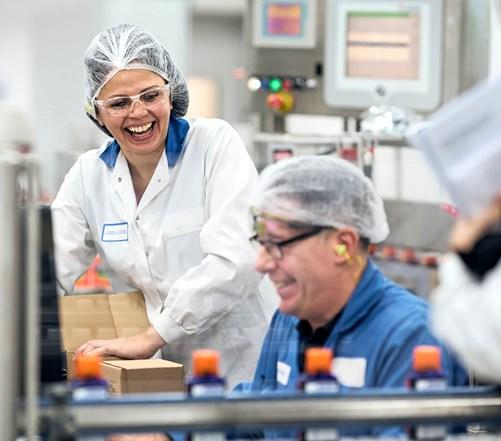 Workers in safety gear in the Reckitt lab in Hull laugh as they work