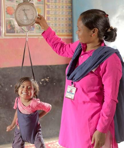Indian woman weighing a child
