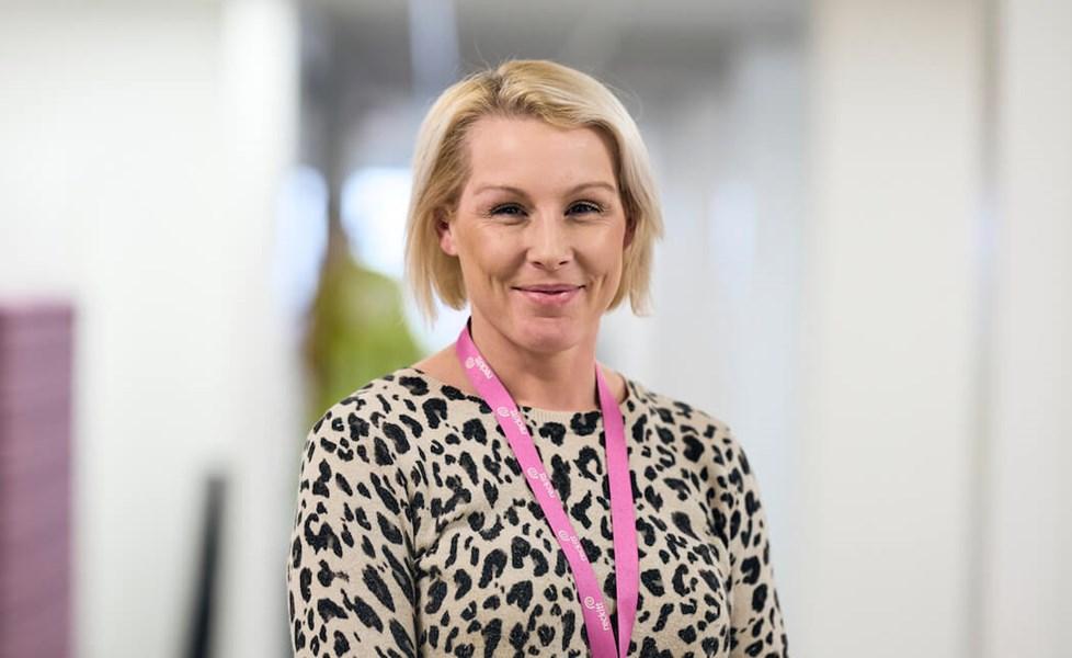 A Reckitt employee in a branded lanyard smiles at the camera