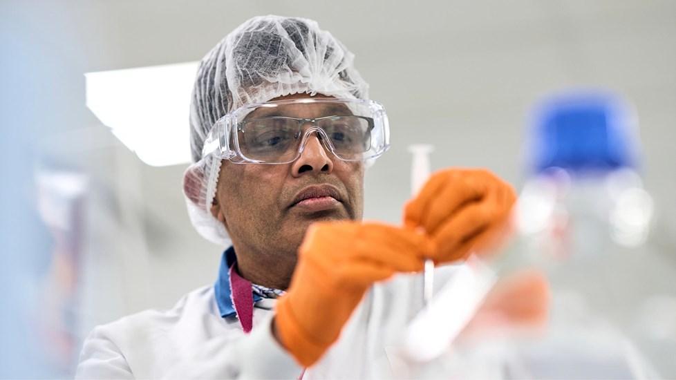 A Reckitt employee in safety gear works with lab equipment