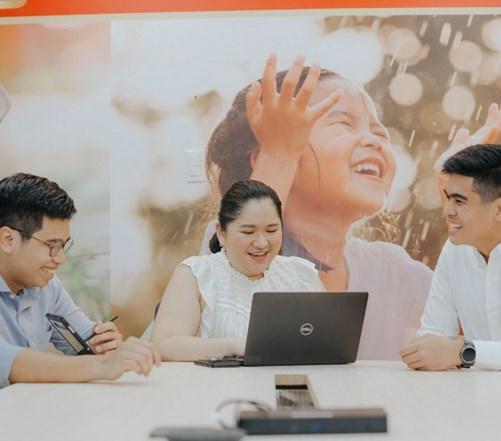 Three colleagues sitting around a laptop