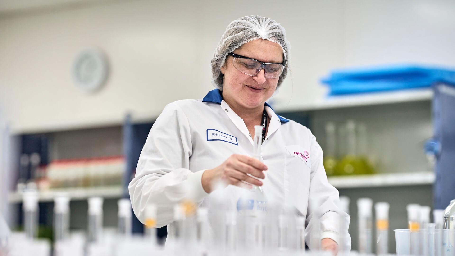 Reckitt employee wearing lab gear inspects a test tube